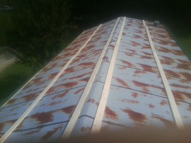 Rusted metal roof panels with new wood purlins before replacement — Storm Damage Roof Repair in Carbon Hill by Roofing Brothers