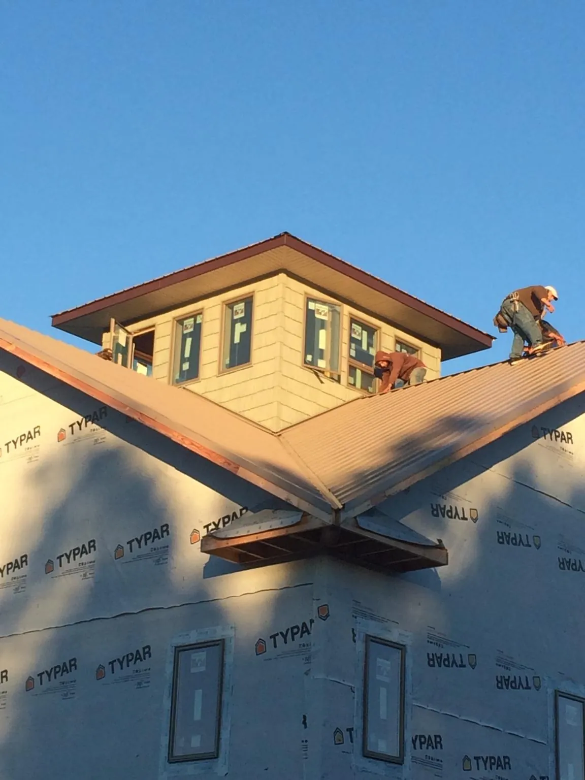 Roofers working around a rooftop cupola on a new metal roof at sunset — Roof Waterproofing in Carbon Hill by Roofing Brothers